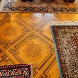 ...e un altro finissimo parquet in legno intarsiato. � caratterizzato da riquadri con greche perimetrali che racchiudono un sovrapposto motivo centrale a stella a otto punte